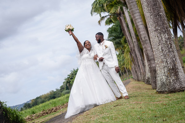 Un couple de jeune mariés exulte de joie dans une palmeraie